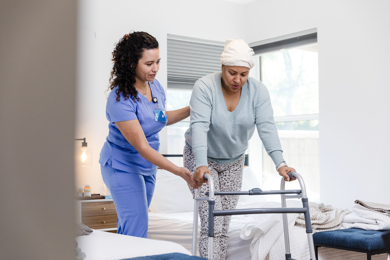 Professional caregiver providing steady support to an elderly man while walking outdoors